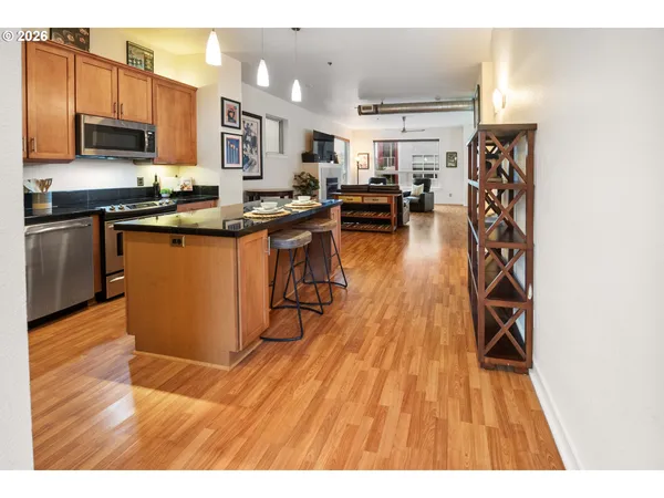 a open kitchen with stainless steel appliances granite countertop a stove top oven a sink dishwasher and cabinets with wooden floor