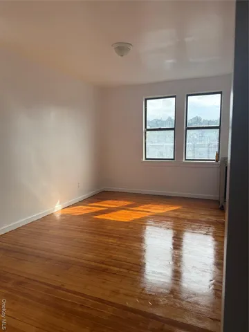 a view of empty room with wooden floor and window