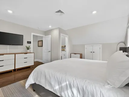 a bedroom with a bed and a flat tv screen on dresser