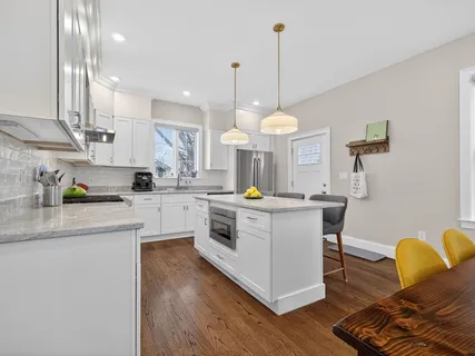 a kitchen with stainless steel appliances granite countertop wooden floors and white cabinets