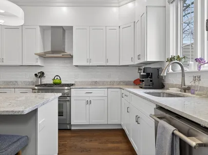 a kitchen with stainless steel appliances granite countertop white cabinets sink and stove