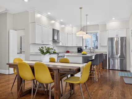 a kitchen with stainless steel appliances granite countertop a dining table chairs refrigerator and cabinets
