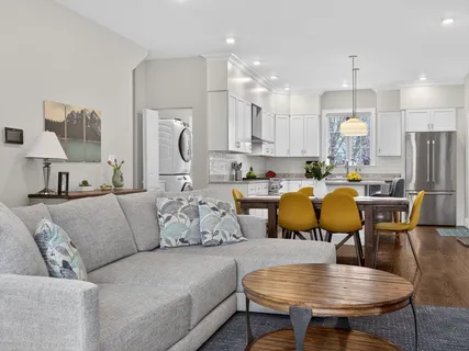 a living room with furniture kitchen view and a chandelier