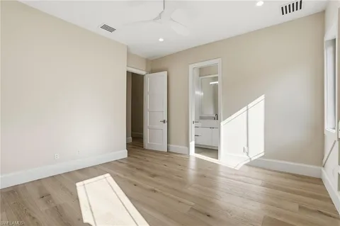 an empty room with wooden floor cabinet and windows