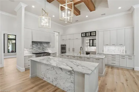 a large kitchen with granite countertop a stove top oven a sink a dining table and chairs with wooden floor