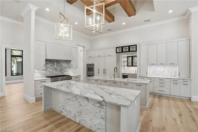 a large kitchen with granite countertop a stove top oven a sink a dining table and chairs with wooden floor