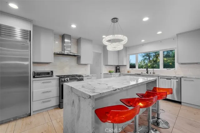 a kitchen with stainless steel appliances granite countertop a sink a stove a refrigerator and island