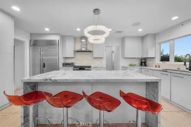 a kitchen with stainless steel appliances granite countertop a dining table chairs stove and white cabinets