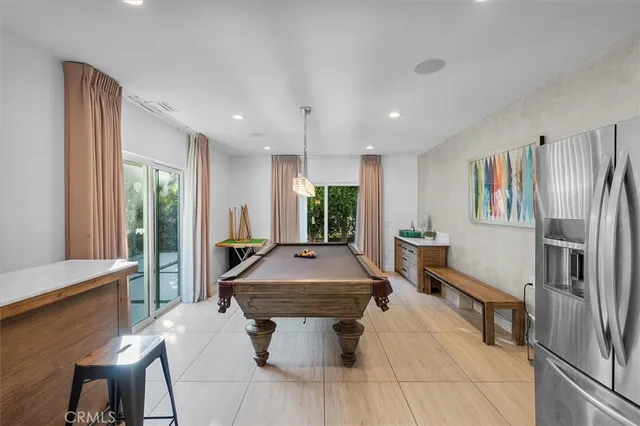 a kitchen with stainless steel appliances granite countertop a refrigerator a sink dishwasher a dining table and chairs with wooden floor