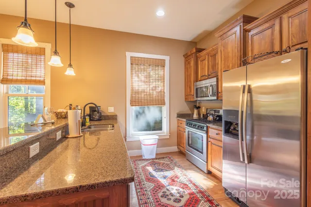 a kitchen with stainless steel appliances granite countertop a refrigerator a stove and a sink with granite countertops