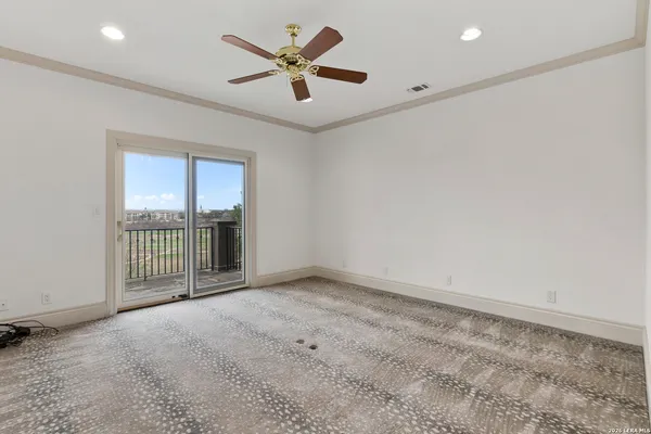an empty room with chandelier fan and windows
