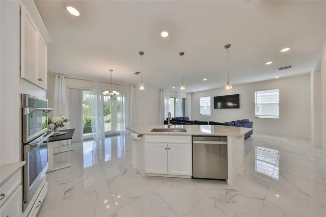 a kitchen with stainless steel appliances kitchen island granite countertop a stove top oven a sink a refrigerator and a granite counter tops