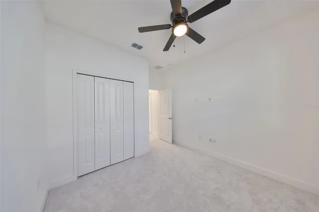 an empty room with closet and a chandelier fan