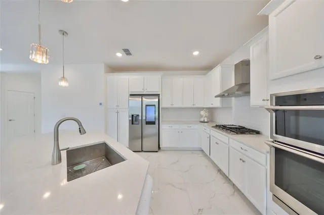 a kitchen with granite countertop a stove a sink and a refrigerator