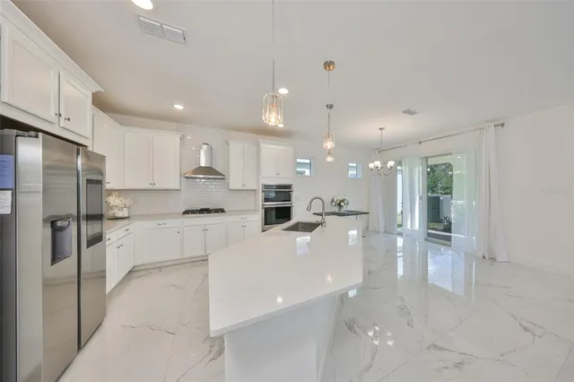 a large white kitchen with a refrigerator a oven and a sink