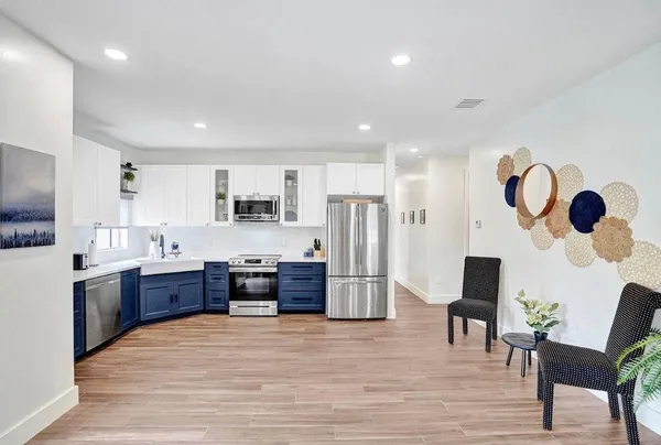 a large kitchen with stainless steel appliances granite countertop a refrigerator and a stove top oven with wooden floor