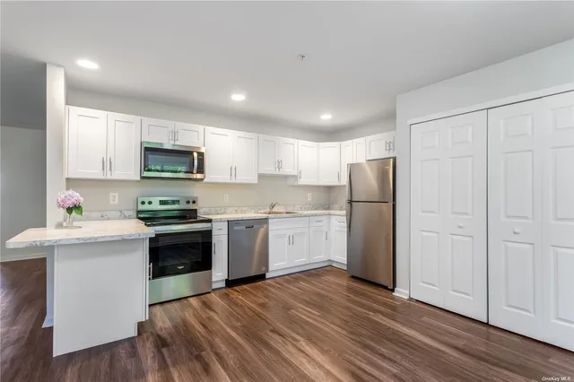 a kitchen with refrigerator a microwave a stove and white cabinets with wooden floor