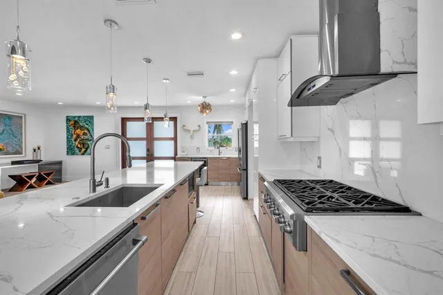 a kitchen with stainless steel appliances a sink a stove top oven a counter space and cabinets