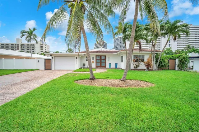 a view of a white house with a big yard and palm trees