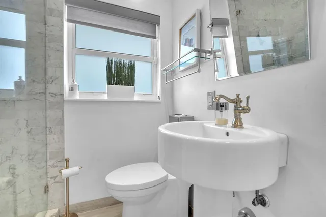 a bathroom with a sink and mirror with toilet