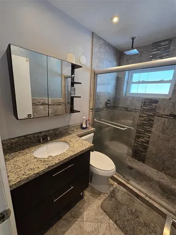 a bathroom with a granite countertop sink toilet and mirror