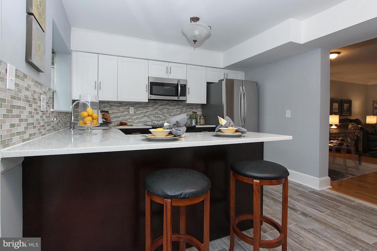 2428 South Walter Reed Drive, Unit A Arlington, VA 22206 - Photo 13 of 30 a kitchen with stainless steel appliances a dining table and chairs in it