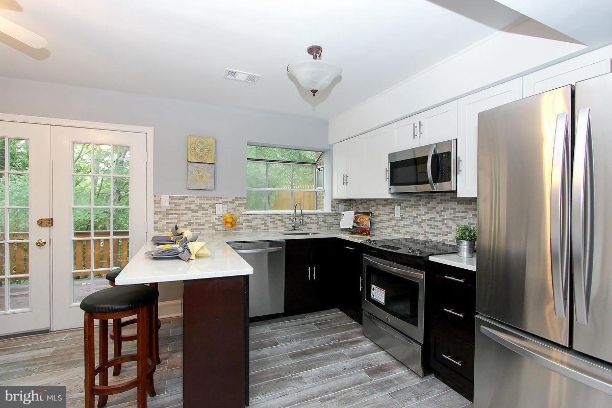 2428 South Walter Reed Drive, Unit A Arlington, VA 22206 - Photo 15 of 30 a kitchen with stainless steel appliances granite countertop a sink stove microwave refrigerator and wooden floor