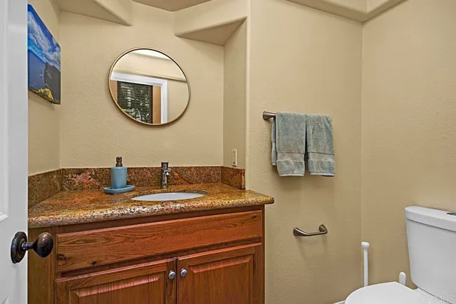 a bathroom with a granite countertop toilet and a sink