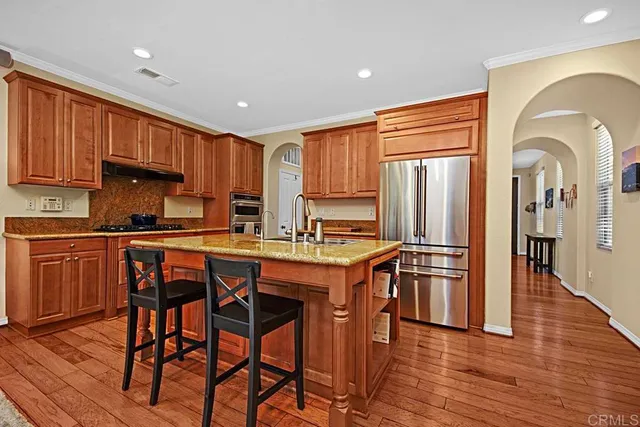 a kitchen with stainless steel appliances granite countertop a refrigerator and wooden cabinets