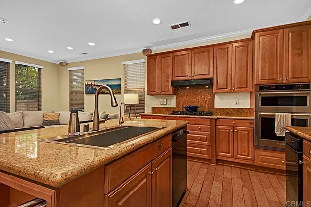 a kitchen with stainless steel appliances granite countertop a sink stove and wooden cabinets