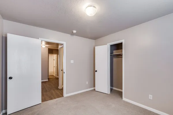 an empty room with closet and a hallway