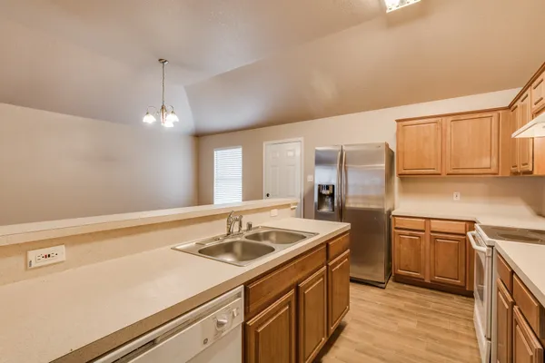 a kitchen with a sink dishwasher a stove and a refrigerator with wooden floor
