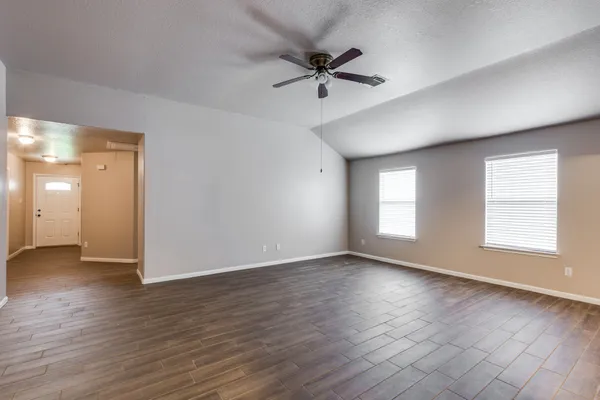 a view of an empty room with wooden floor and a window