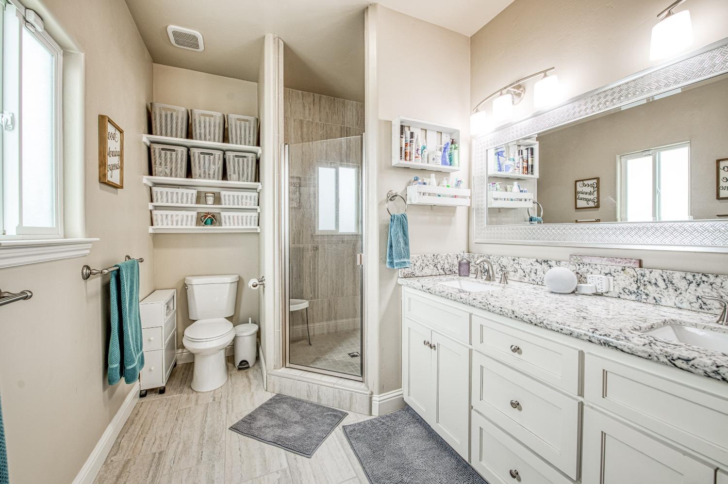 36919 Ave 17 1/2 Madera, CA 93636 - Photo 34 of 77 a bathroom with a granite countertop sink a toilet a shower and a mirror