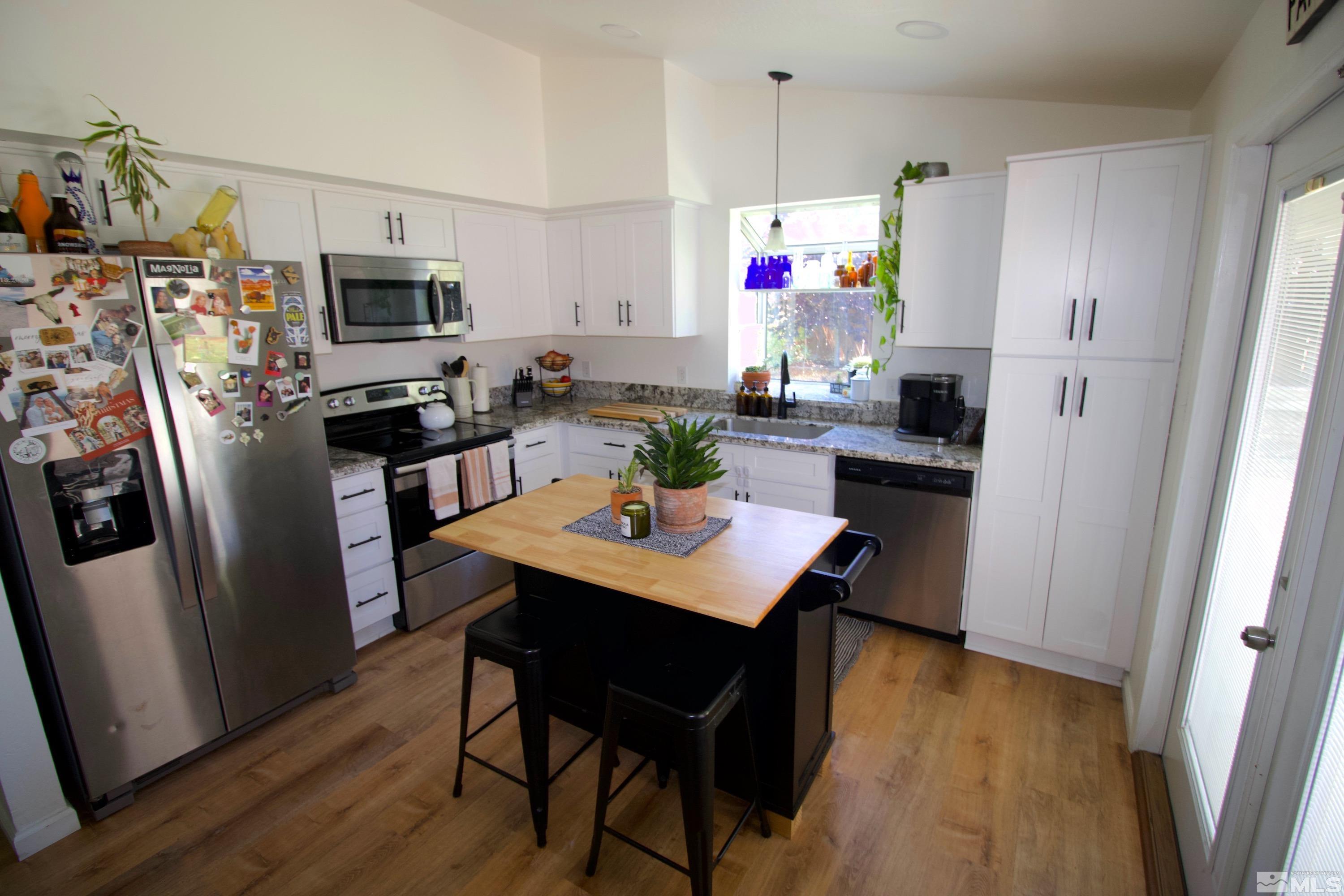 6350 Moon Ridge Terrace Reno, NV 89523 - Photo 10 of 19 a kitchen with stainless steel appliances a stove a refrigerator a sink dishwasher a dining table and chairs with wooden floor