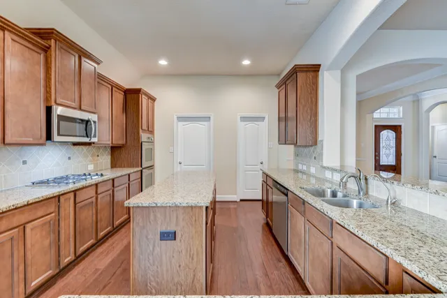 a kitchen with stainless steel appliances granite countertop wooden cabinets a stove and a sink