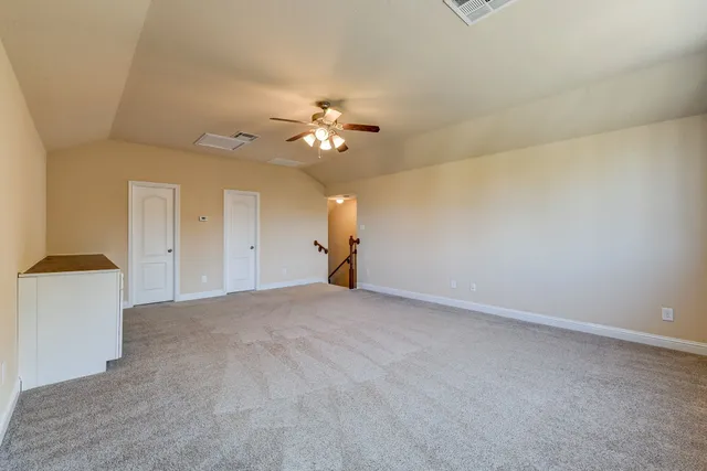 a view of an empty room and chandelier fan