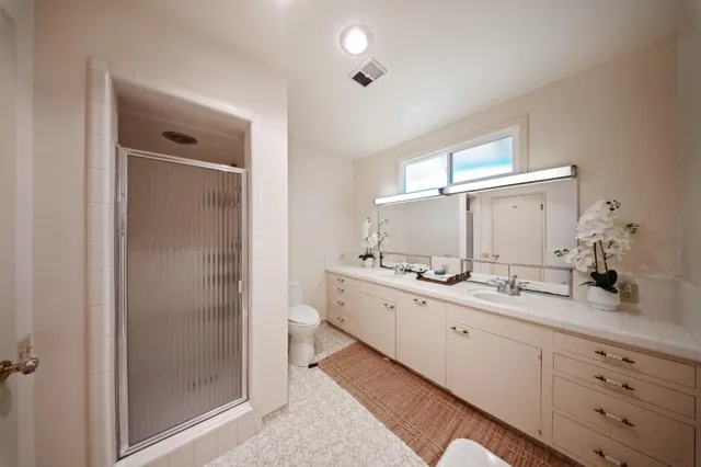 a bathroom with double vanity sink a mirror and a shower