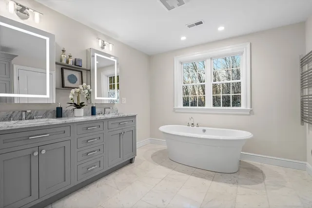 a spacious bathroom with a double vanity sink mirror and bathtub