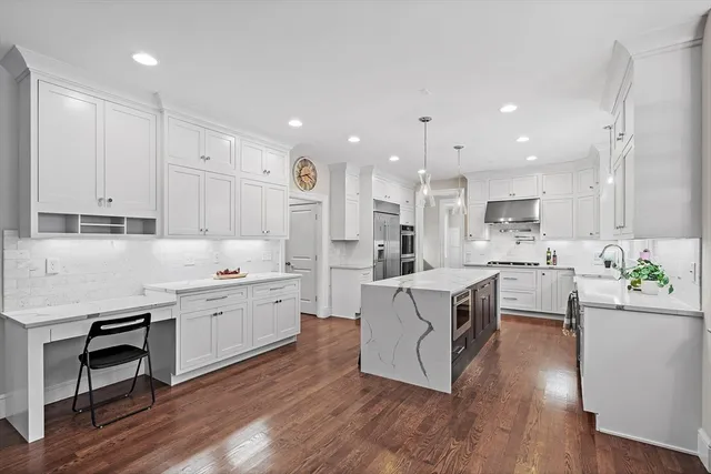 a large white kitchen with stainless steel appliances granite countertop a lot of counter space and wooden floors