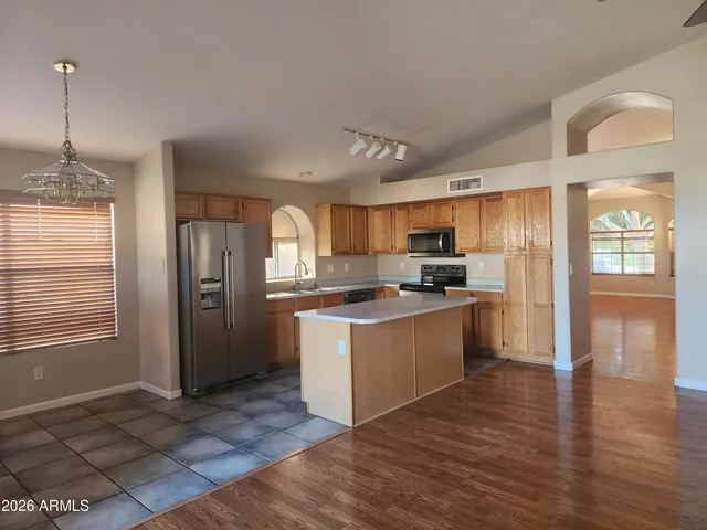 a kitchen with stainless steel appliances granite countertop a refrigerator a sink dishwasher a stove with wooden cabinets and floor