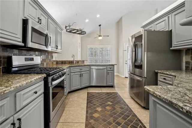 a kitchen with stainless steel appliances granite countertop a sink and dishwasher a stove with wooden cabinets