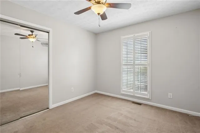 an empty room with ceiling fan and windows