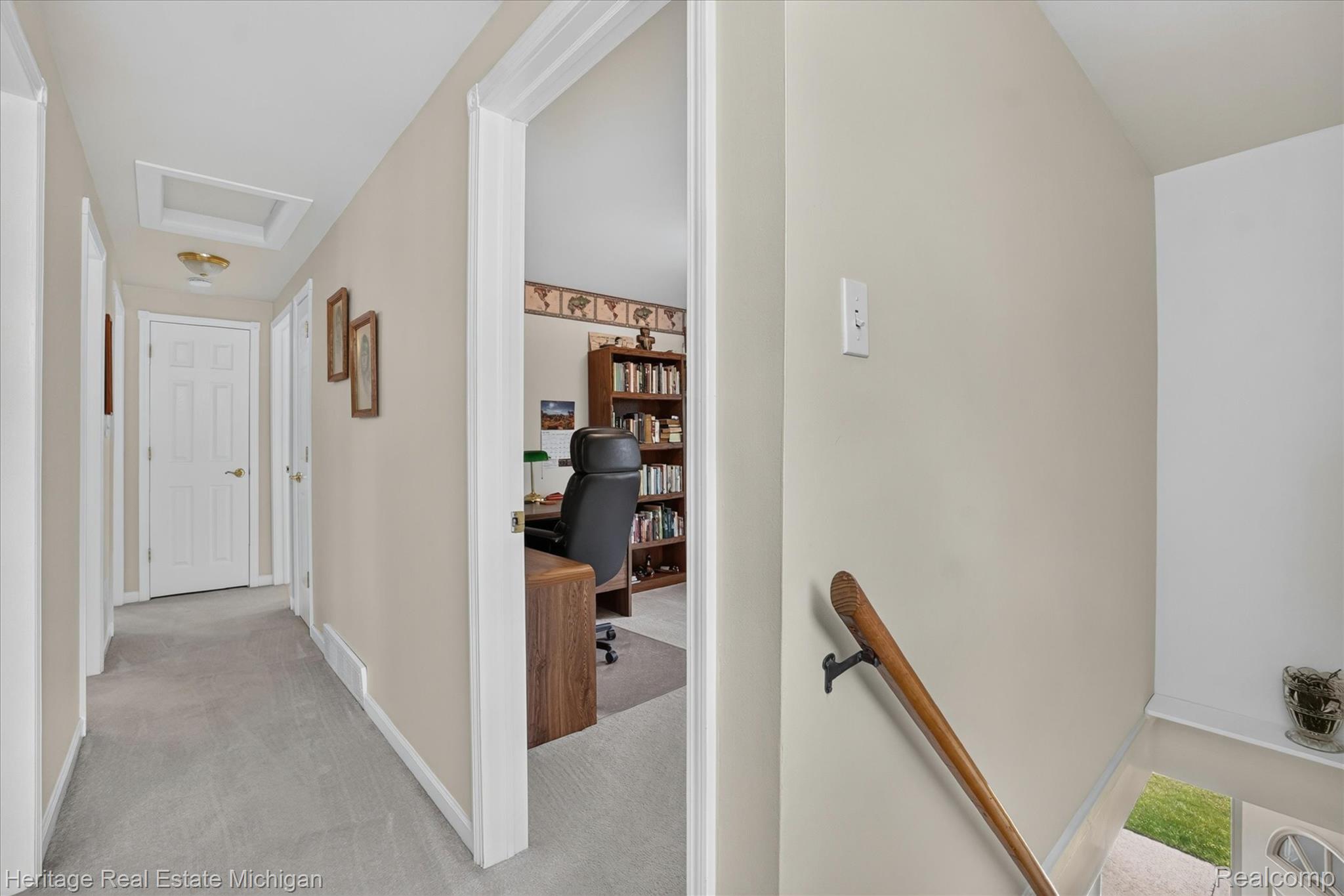 14038 North Hogan Road Linden, MI 48451 - Photo 34 of 53 Carpeted hallway featuring multiple white paneled doors, ceiling-mounted light fixture, and an attic access panel