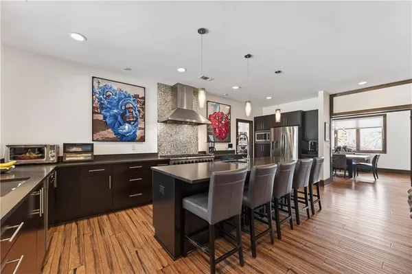 a kitchen with stainless steel appliances kitchen island granite countertop a table chairs sink and cabinets