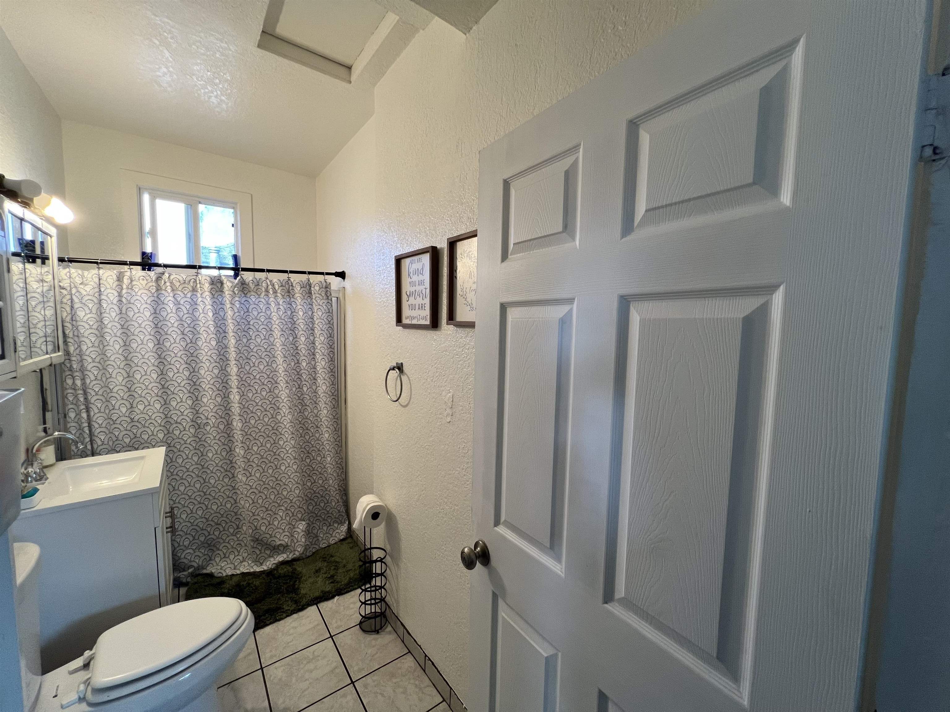 1803 Rosedale Avenue Oakland, CA 94601 - Photo 15 of 28 Full bath featuring a textured wall, vanity, a shower with shower curtain, light tile patterned floors, and a textured ceiling