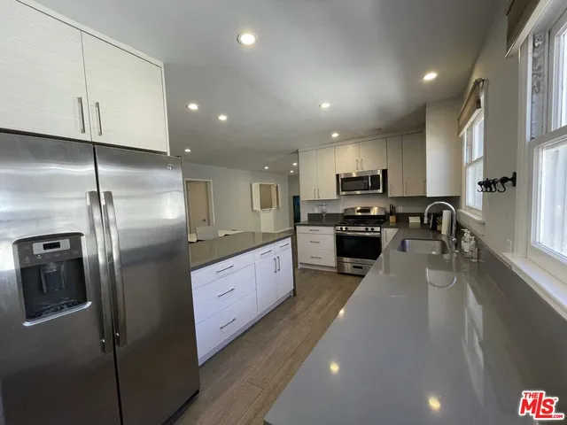 a kitchen with stainless steel appliances granite countertop a refrigerator a sink a stove and a refrigerator with wooden floor