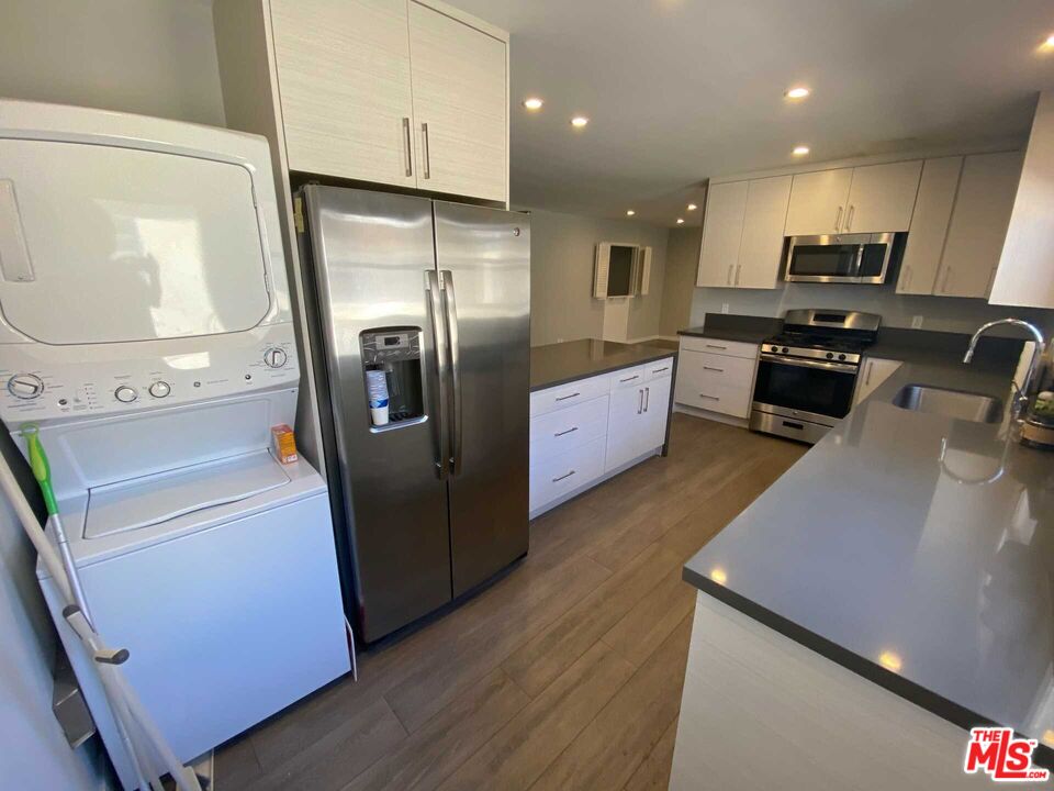 348 South Elm Drive, Unit 6 Beverly Hills, CA 90212 - Photo 7 of 17 a kitchen with stainless steel appliances a refrigerator a sink a stove a microwave oven and a dining table with wooden floor