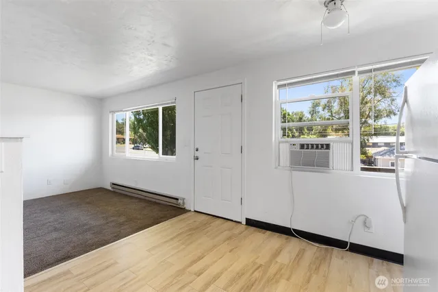 a view of empty room with wooden floor and fan
