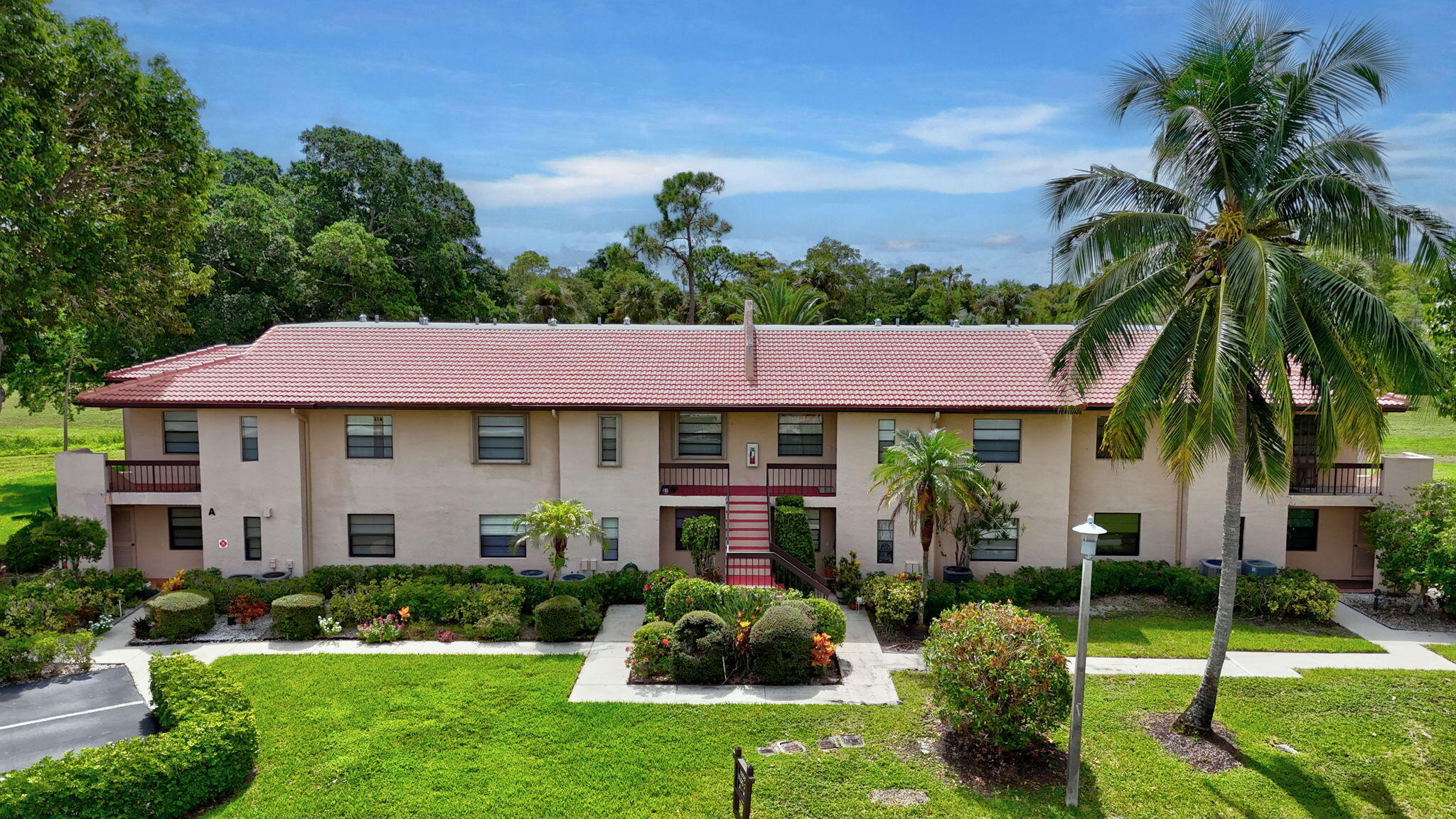 9268 Vista Del Lago, Unit 26D Boca Raton, FL 33428 - Photo 28 of 34 a front view of a house with a yard and potted plants